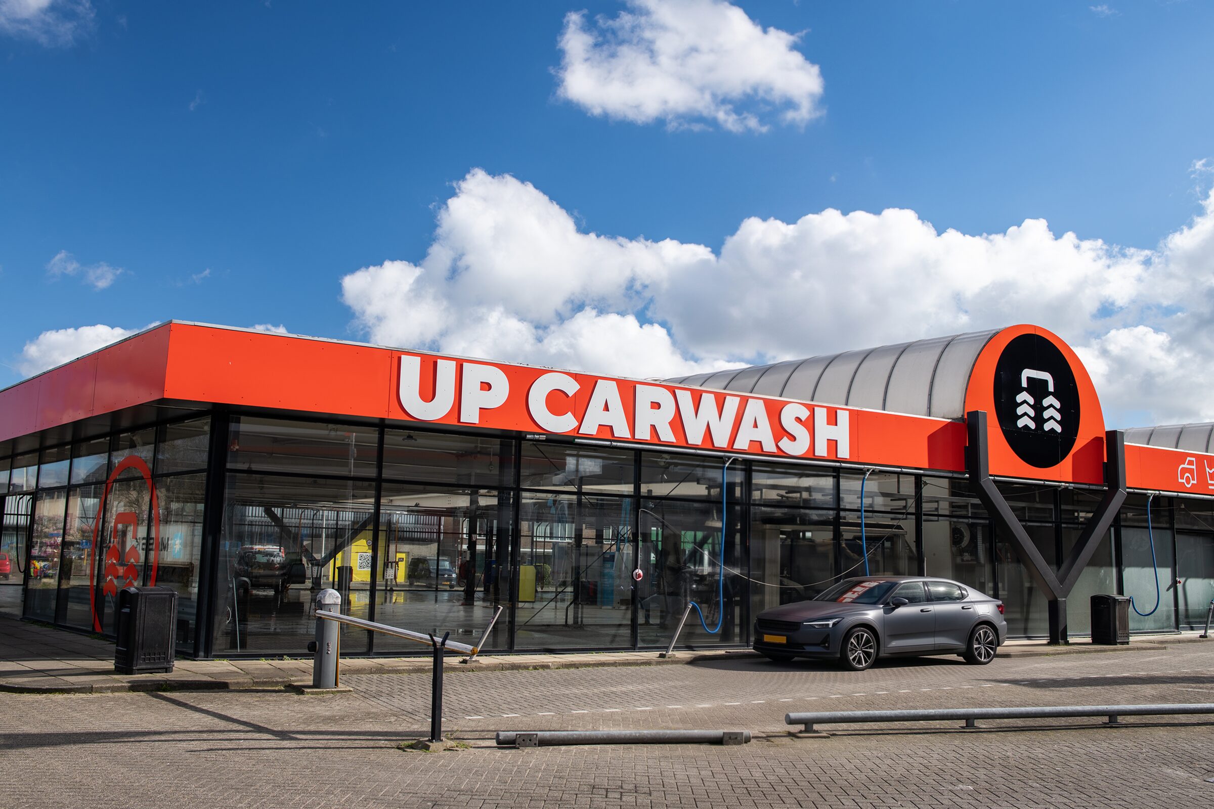 De gevel van UP Carwash Beverwijk, met de oranje luifel en de vlag